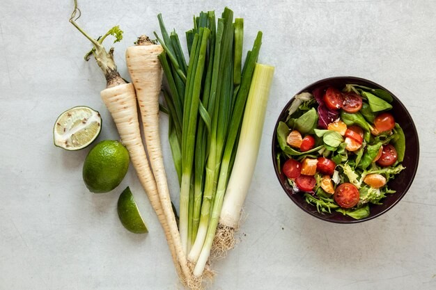 Bowl with salad and vegetables beside