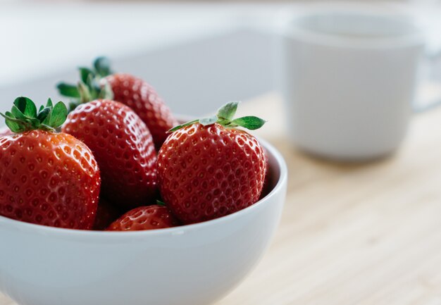 Bowl with strawberries on blurred background