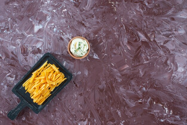 대리석 테이블에 보드에 요구르트와 감자 튀김 한 그릇.