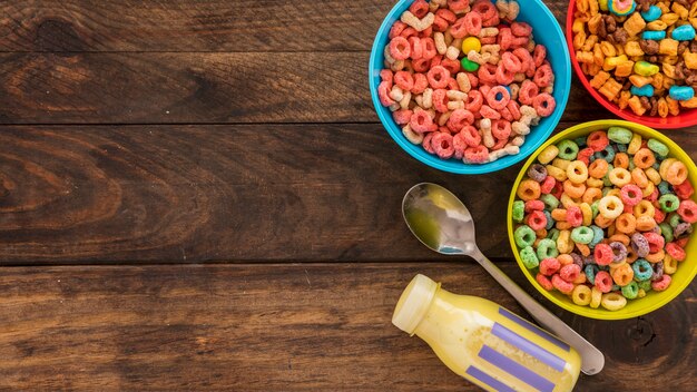 Bowls of cereals with milk bottle and spoon 