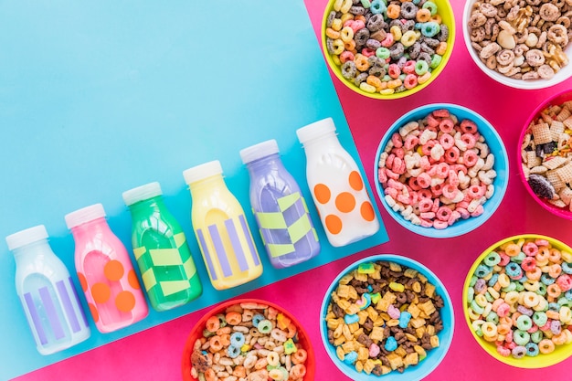 Foto gratuita ciotole di cereali con piccole bottiglie di latte