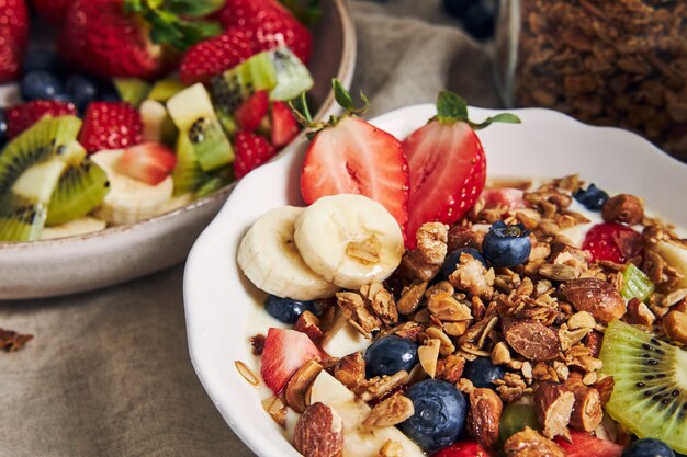 Bowls of granola with yogurt, fruits and berries on a white surface