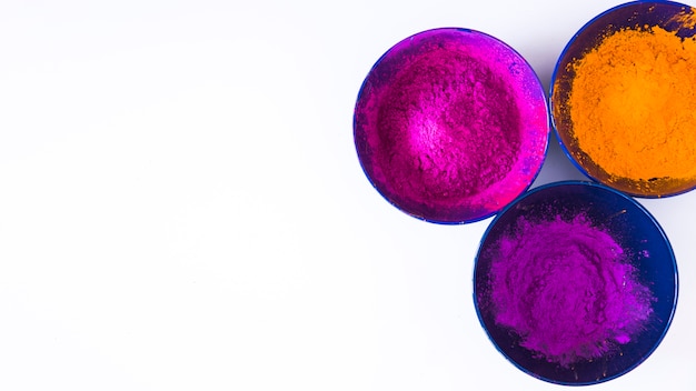 Bowls of holi color powder on white background