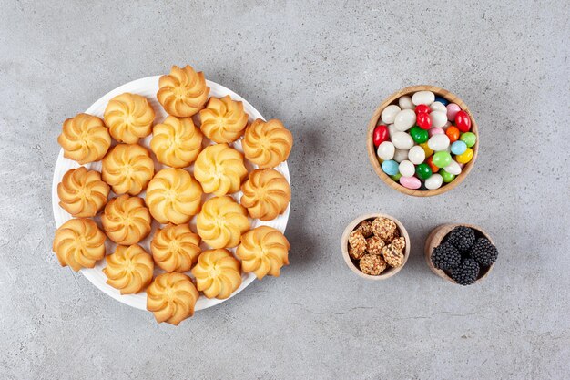 Bowls of mullberries, candies and peanuts homemade cookies on a plate on marble background. High quality photo