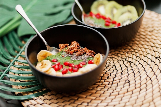 Bowls topped with kiwi, granola, garnet, chia and avocado