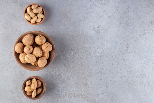 Bowls of various types of healthy nuts placed on a stone background. 