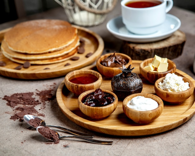 bowls with appetizers on wooden tray