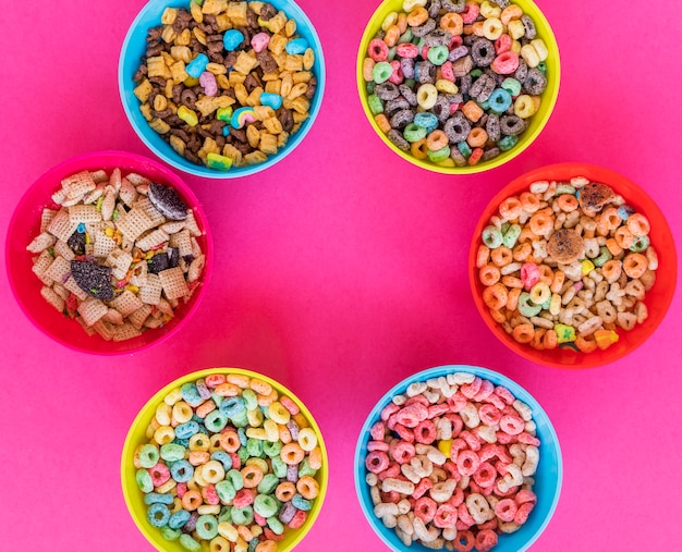 Bowls with different cereals on pink table