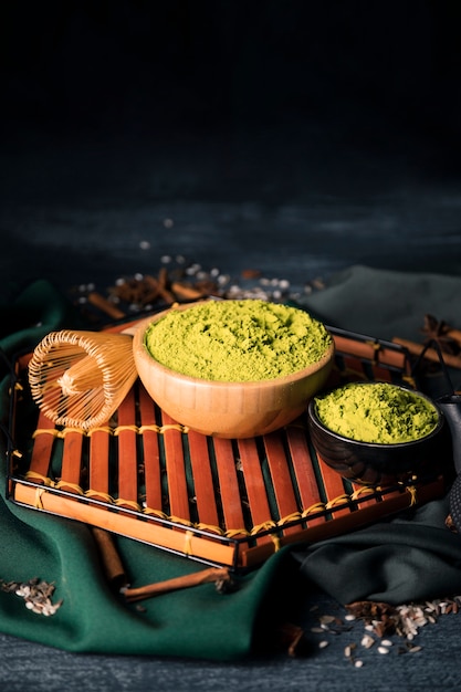 Free photo bowls with green matcha on wooden tray