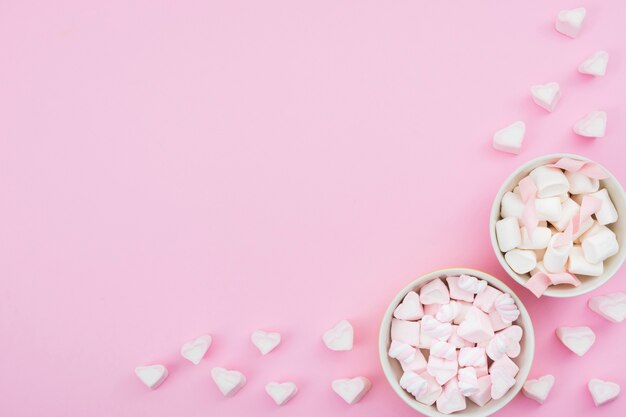 Bowls with meringue on pink background