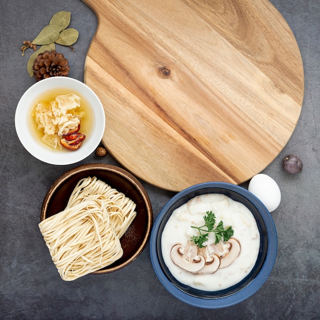 麺と木製のサポートと灰色の背景にキノコのスープボウル