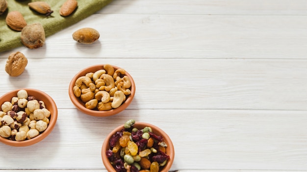 Free photo bowls with nuts near green cloth