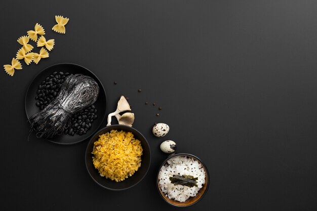 Bowls with rice and pasta on a dark background