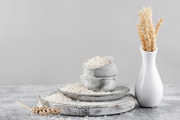 Free photo bowls with rice and vase with grains