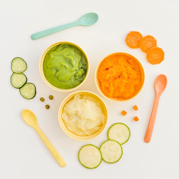 Bowls with vegetables puree for baby and spoons