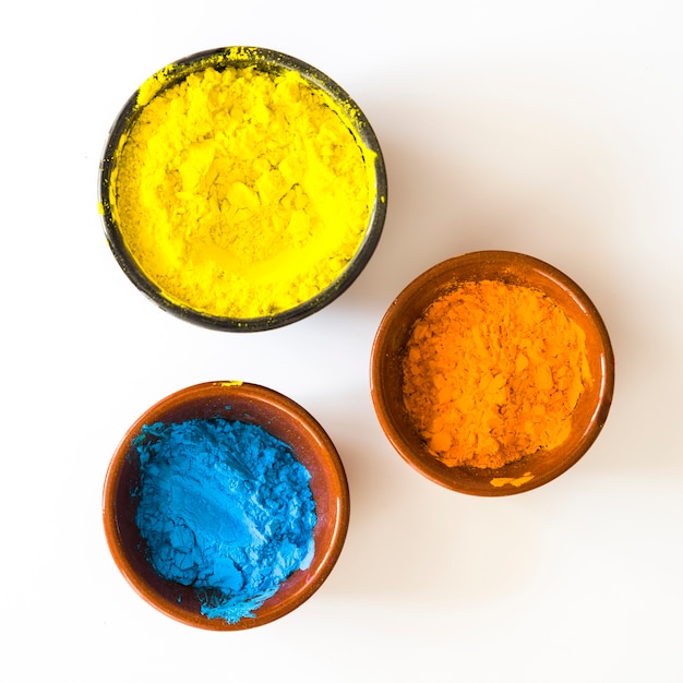 Bowls of yellow; orange and blue color powder isolated on white background