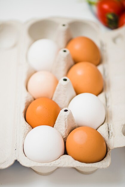 Box of eggs on table near tomatoes