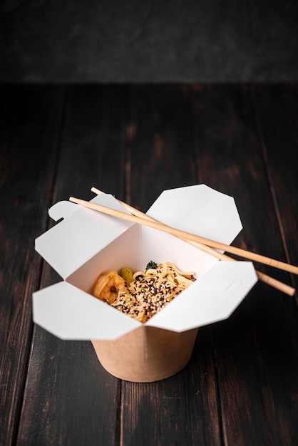 Free photo box of of noodles with sesame seeds and chopsticks