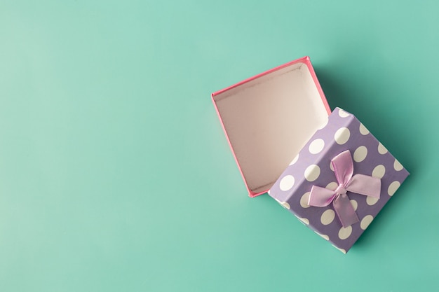 Box of present with bow on light green background