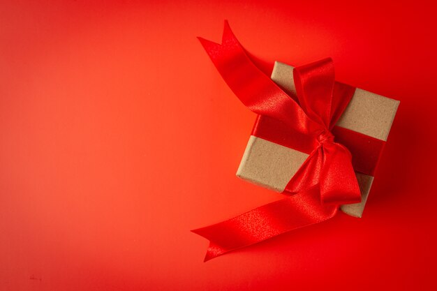 Box of present with red ribbon bow on red background