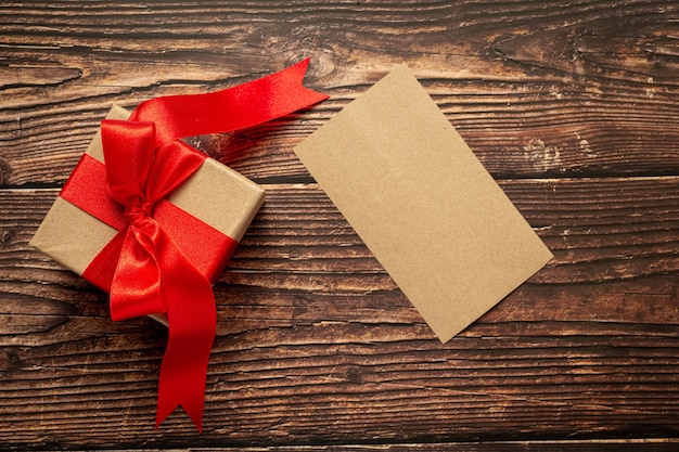 Free photo box of present with red ribbon bow on wooden background