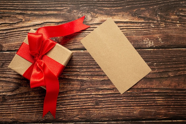 木製の背景に赤いリボンの弓とプレゼントの箱