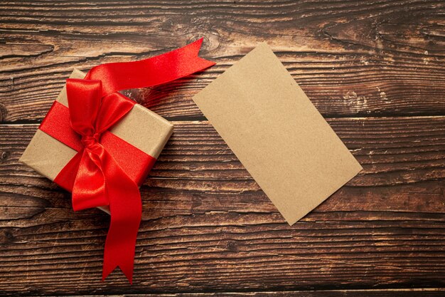 나무 바탕에 빨간 리본 활과 선물 상자