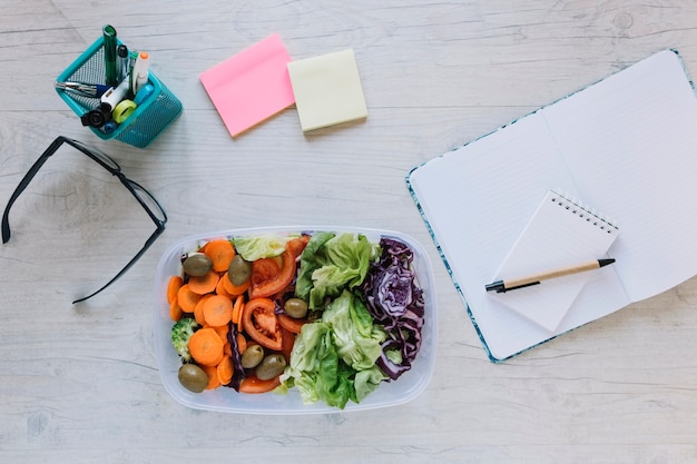 Foto gratuita scatola con insalata sul tavolo dell'ufficio