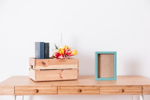 Box with tulips and books near frame