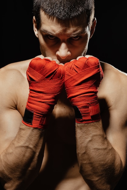 Боксер мужского пола, позирует в уверенной оборонительной позиции с руками в бинтах