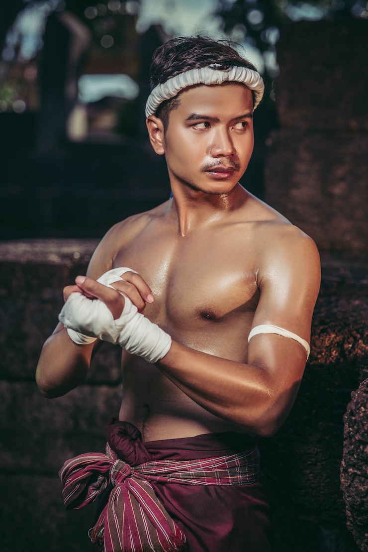 Free Photo the boxer sat on the stone, tied the tape around his hand, preparing to fight.