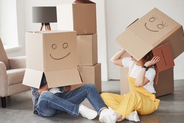 Boxes on the heads. Happy couple together in their new house. Conception of moving