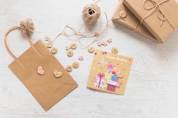 Boxes; string spool; paper shopping bag; buttons and birthday greeting card on white textured background