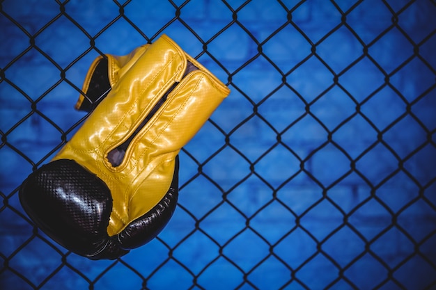 Боксерская перчатка висит на заборе из проволочной сетки