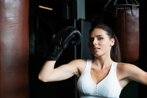 Boxing woman posing with punching bag. Strong and independent woman concept