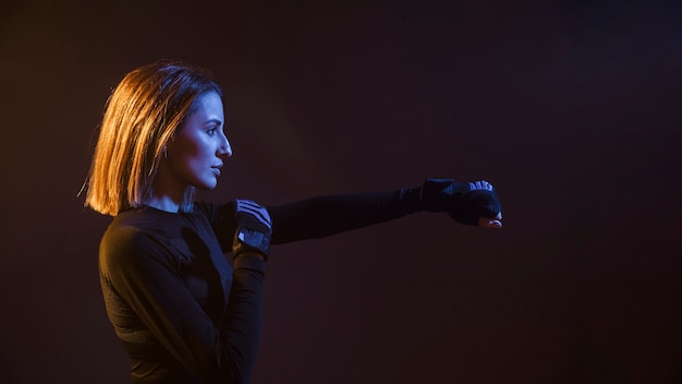 Boxing woman punching with hand in dark