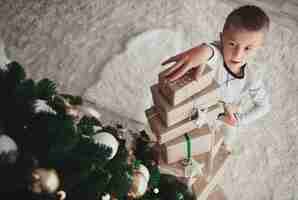 Foto gratuita ragazzo che organizza pila di regali di natale