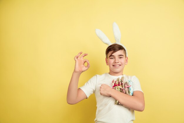Boy as an Easter bunny on yellow studio wall