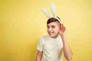 Foto gratuita ragazzo come un coniglietto di pasqua sulla parete gialla dello studio