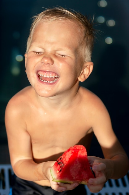Бесплатное фото Мальчик у бассейна с арбузом