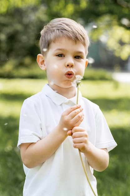 Free photo boy blowing a flower in the wind
