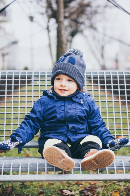 boy in blue jacket sitting on a bench