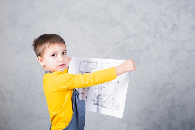 Boy builder holding paper with project