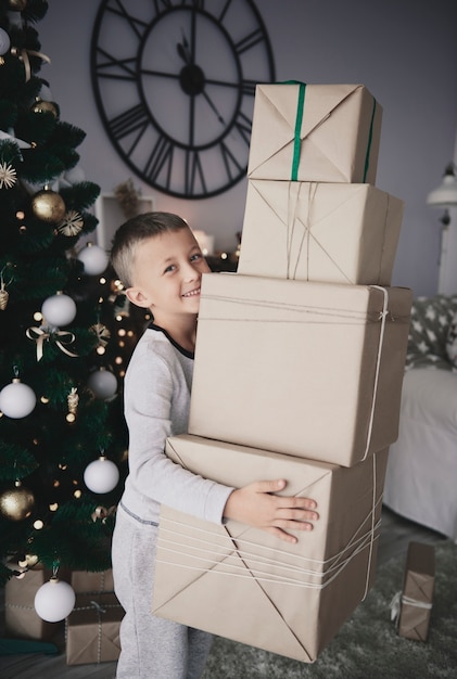 Free photo boy carrying stack of gifts