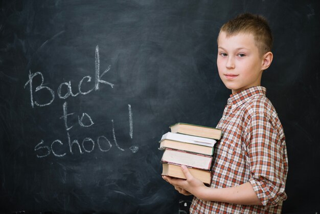 Boy in checkered shirt holding books