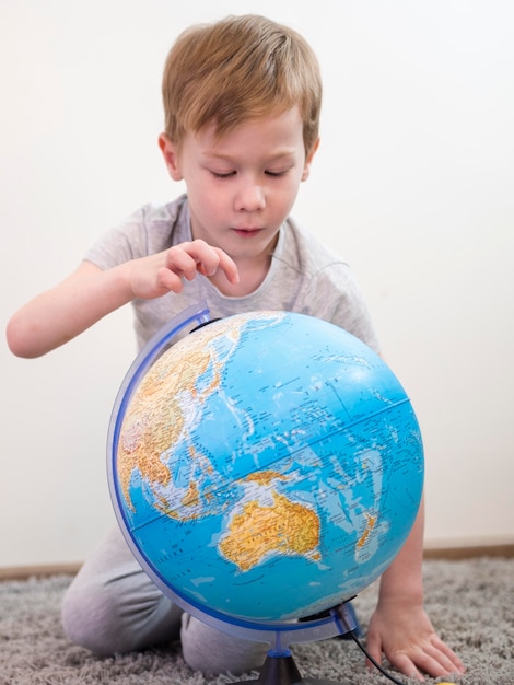 Foto gratuita ragazzo che controlla un globo terrestre