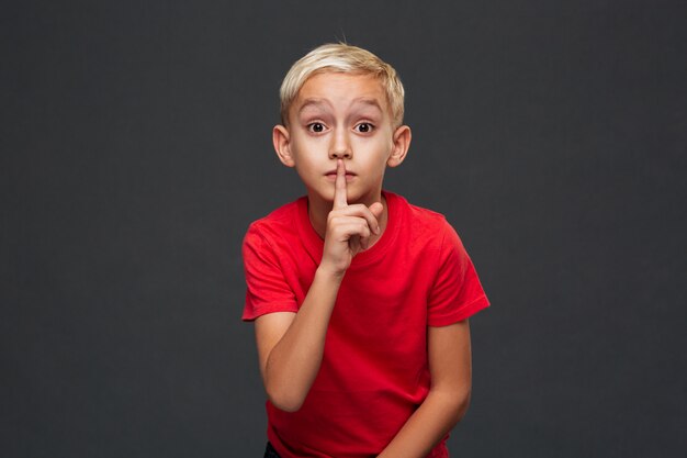 Boy child showing silence gesture.