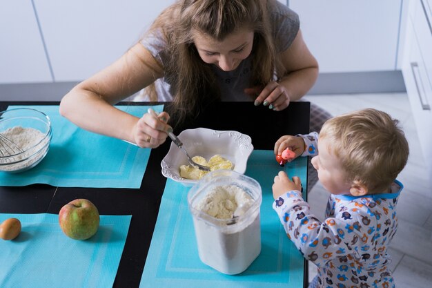 Bambino del ragazzo con la mamma che cucina nella torta della cucina