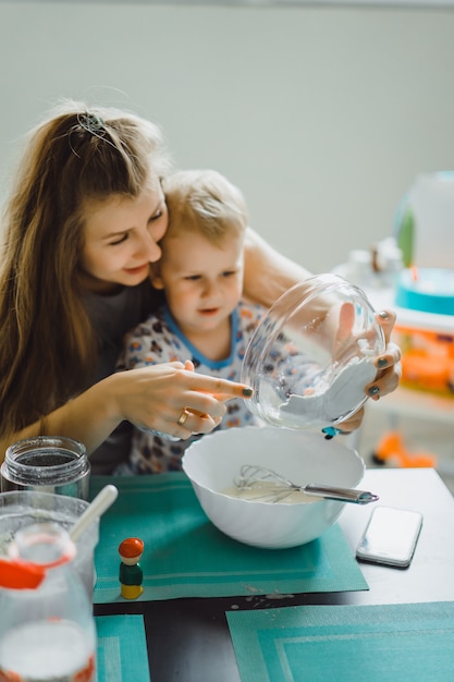 Bambino del ragazzo con la mamma che cucina nella torta della cucina