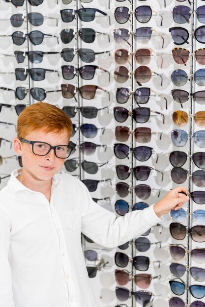 Boy choosing eyeglasses looking at camera in optica